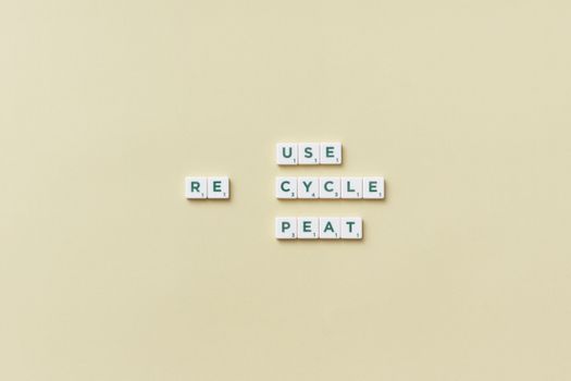 Letter tiles spelling 'reuse recycle repeat' on a simple background, promoting sustainability.