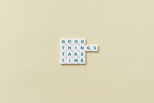 Minimalist image with Scrabble tiles spelling 'Good Things Take Time' on a neutral backdrop.