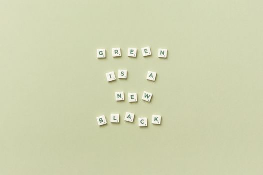 Scrabble tiles spell 'Green is the New Black' on a plain background, promoting eco-friendliness.