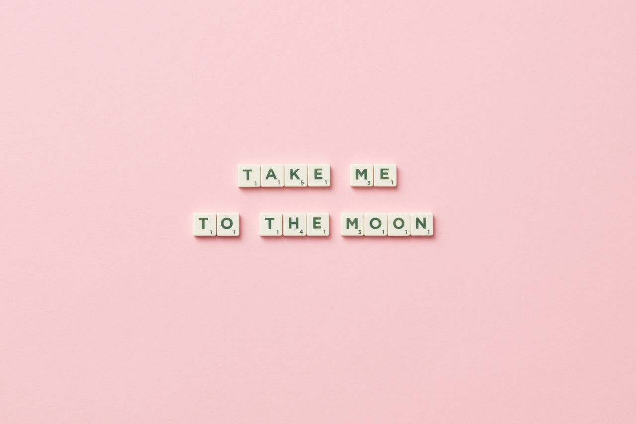 scrabble letters arranged to say take me to the moon on a pink backgro