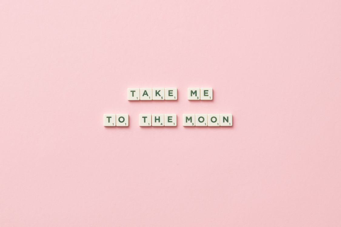 Free Scrabble letters arranged to say 'Take Me to the Moon' on a pink background. Stock Photo