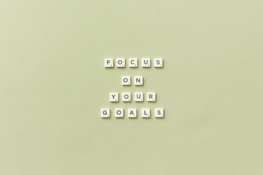 Scrabble letters forming a motivational phrase 'Focus on Your Goals' on a light green background.