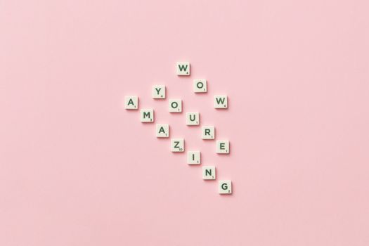 Motivational message formed with alphabet tiles on a pastel pink background.