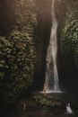Woman in Black Tank Top and Blue Denim Shorts Standing in Front of Waterfalls