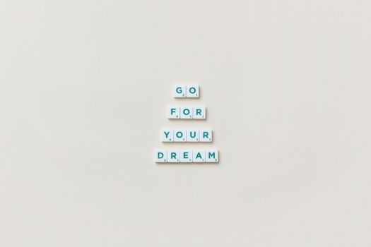 Inspirational text 'Go For Your Dream' made from Scrabble tiles on a plain background.