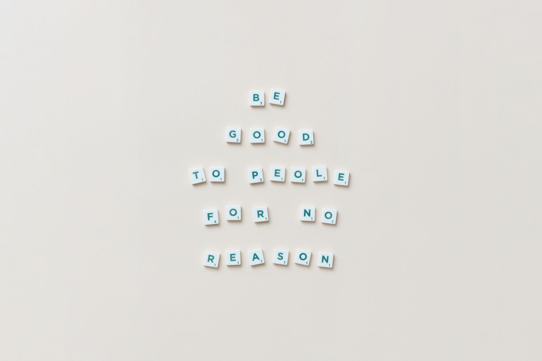 Scrabble tiles spell 'Be good to people for no reason' on a white background.