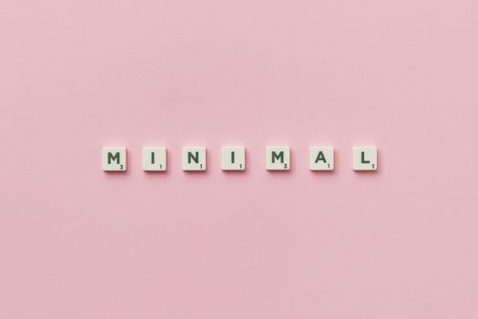 Scrabble tiles spelling 'minimal' on a pink background, showcasing minimalist design.