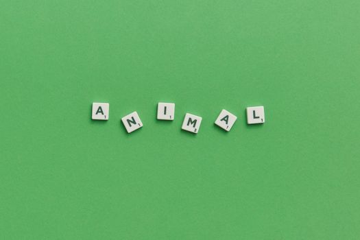 Scrabble tiles spelling 'animal' on a vibrant green background, providing conceptual space.