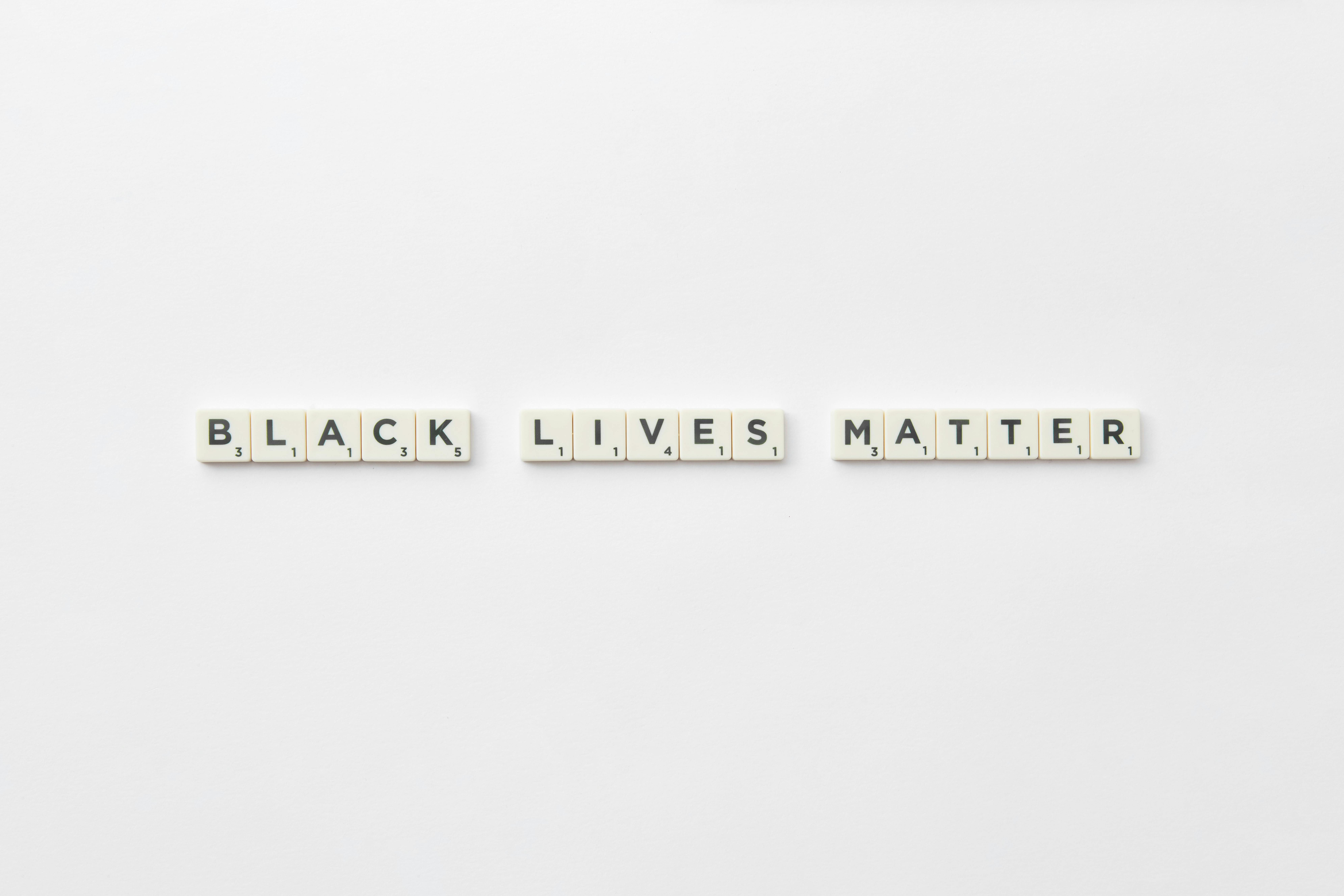 Scrabble letter tiles spelling Black Lives Matter on a white background, with ample copyspace.