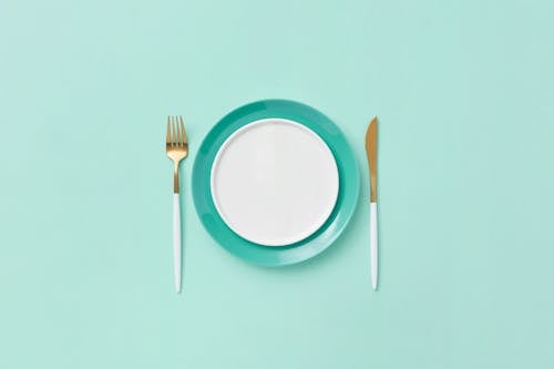 Free Plate, Fork and Knife on Teal Background Stock Photo