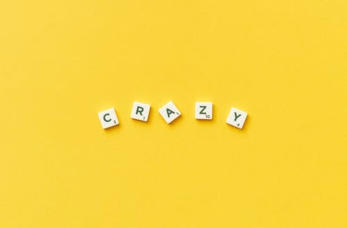 Crazy Spelled in Scrabble Letters on Yellow Background