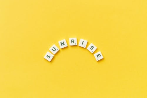 Abstract Description of Sunrise by Scrabble Tiles on Yellow Background