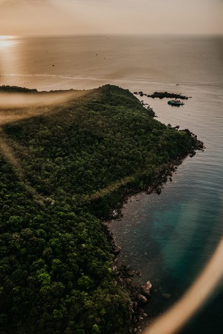 Stunning aerial view of Vietnam's lush coastline at sunset, showcasing vibrant greenery and tranquil waters.