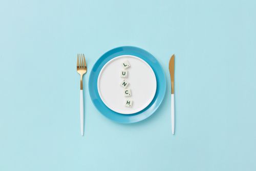 Free Flat lay of a lunch setting with Scrabble letters spelling 'lunch' on a blue plate and cutlery. Stock Photo
