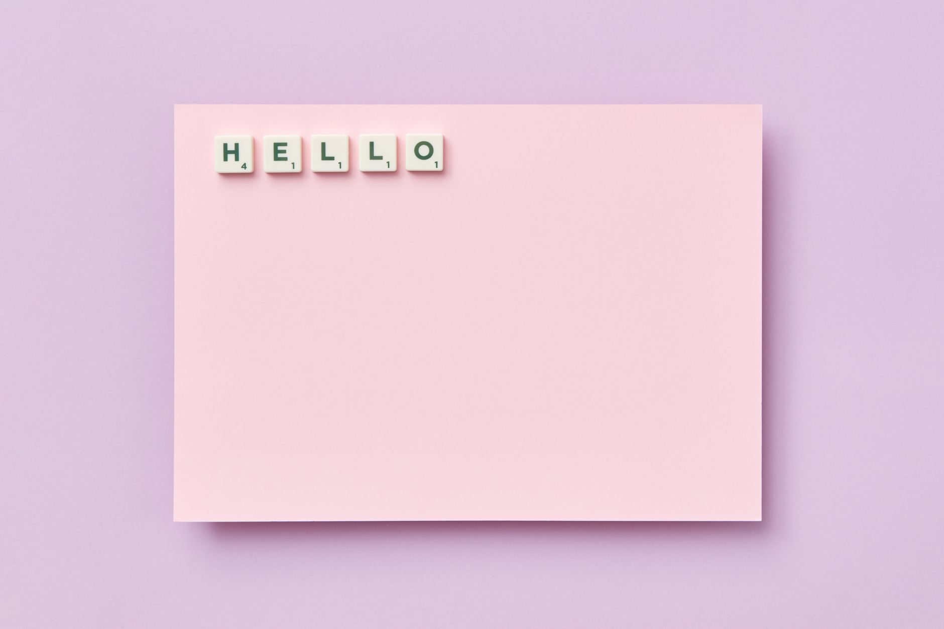 Pink card featuring the word 'Hello' spelled with Scrabble tiles on a pastel background. — photo by DS stories