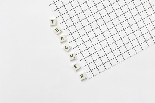 Alphabet letters spelling 'Teacher' on a white grid paper, highlighting education theme.