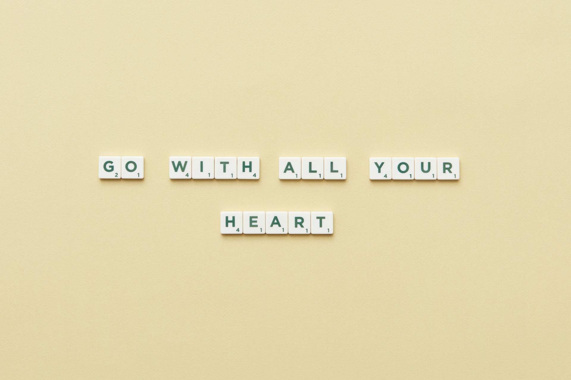 Motivational message 'Go With All Your Heart' displayed using Scrabble tiles on a beige background.