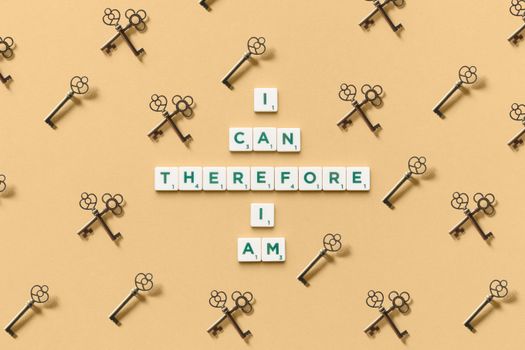 Inspirational phrase made from tiles surrounded by decorative keys on a beige background.