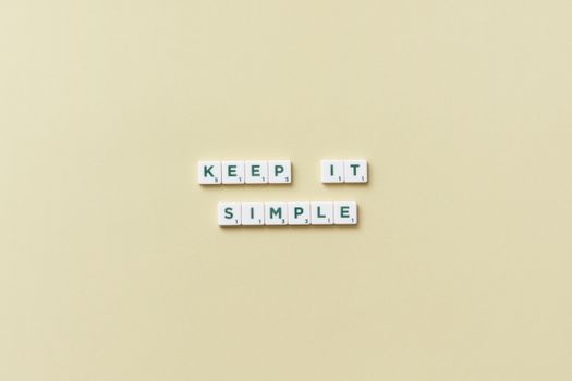Simple message with Scrabble tiles on a pastel background promoting minimalism.