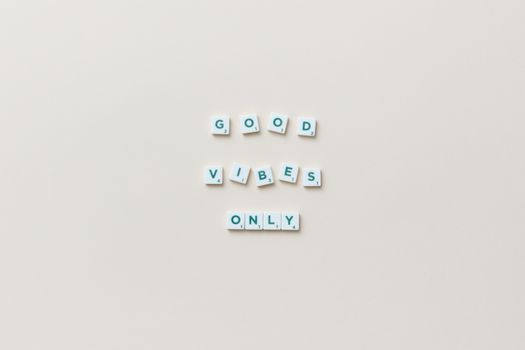Flat lay of Scrabble tiles spelling 'Good Vibes Only' on a white background.