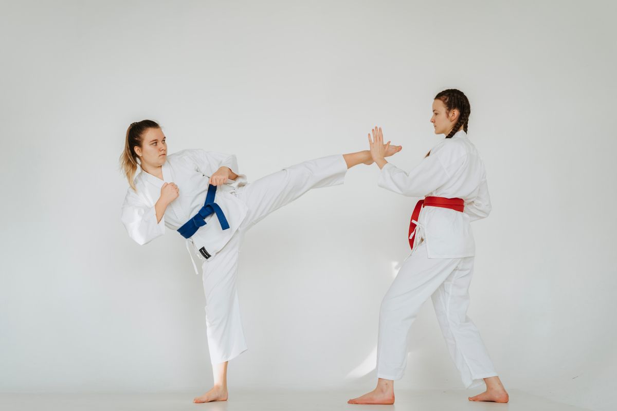 Two women karate athletes exchanging kicks