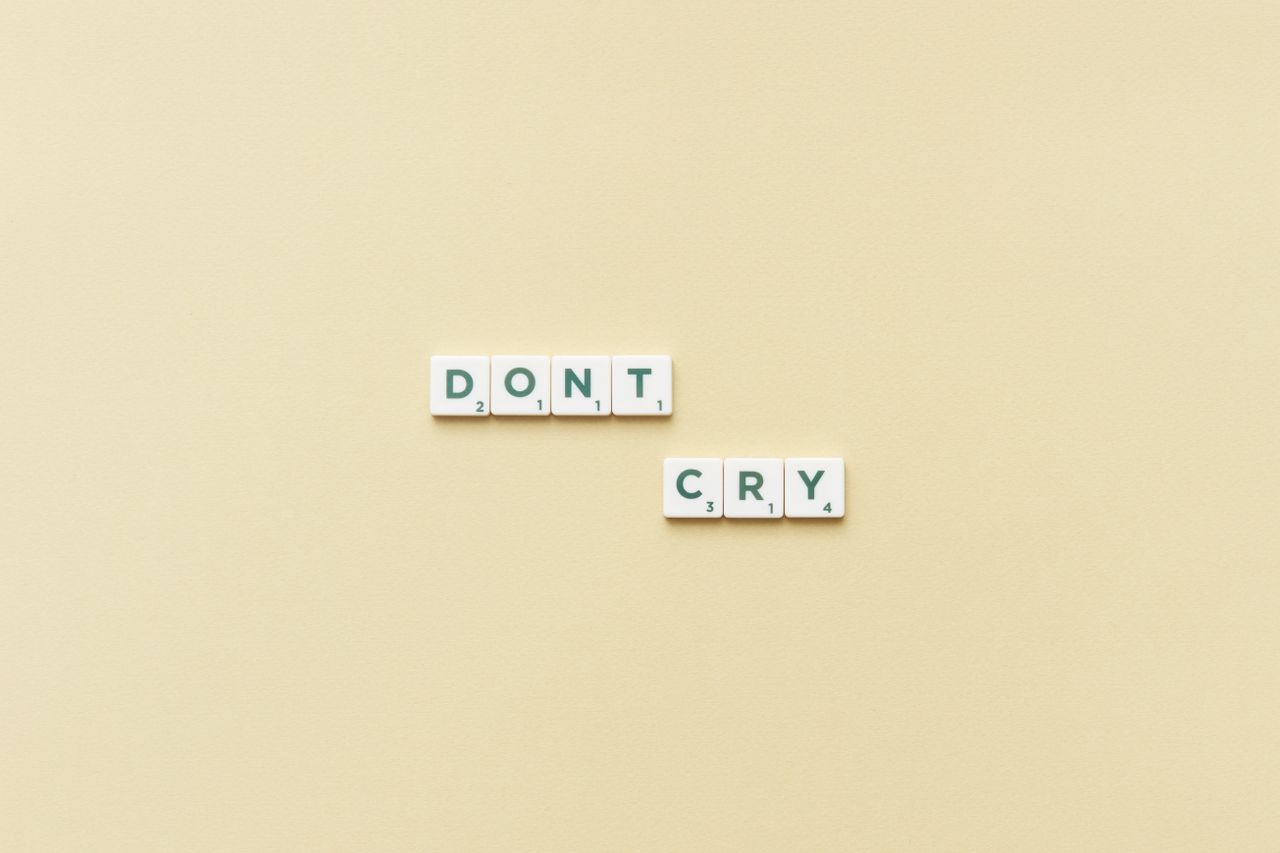 scrabble tiles forming the phrase don t cry on a simple yellow backgro