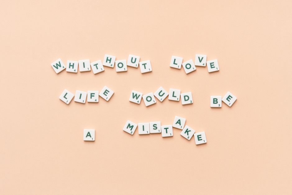 Scrabble tiles forming the phrase 'Without love life would be a mistake' on a beige background.