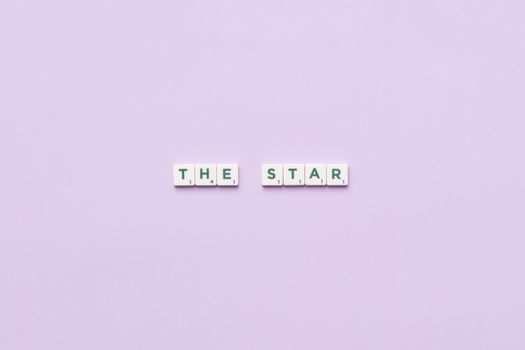 Scrabble tiles spelling 'The Star' on a soft pastel background, providing clean copy space.