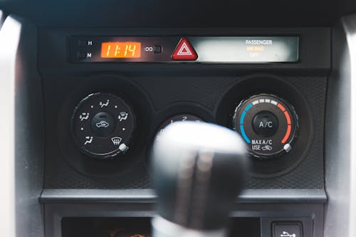 Blurred gear shift against dashboard with buttons and electronic clock in car in daytime