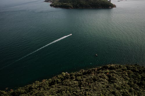 Free White Boat on Sea Near Green Island Stock Photo
