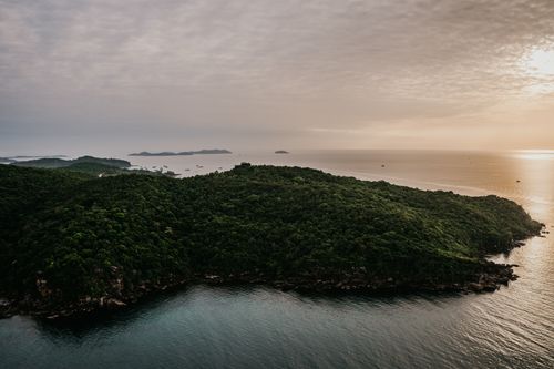 Free Stunning aerial view of lush green Vietnamese coastline and ocean at sunset, capturing nature's beauty. Stock Photo
