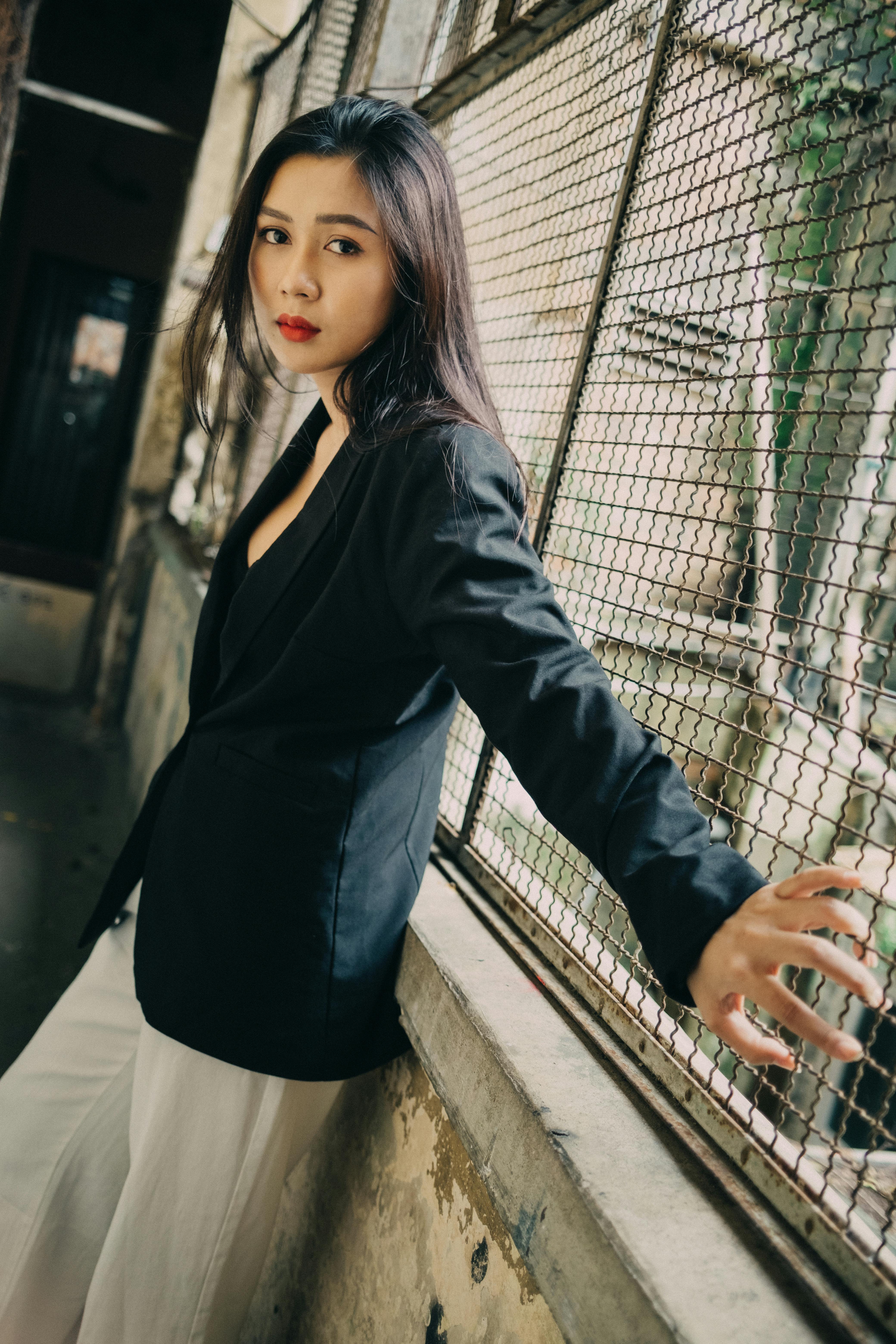 trendy young ethnic lady standing near fence