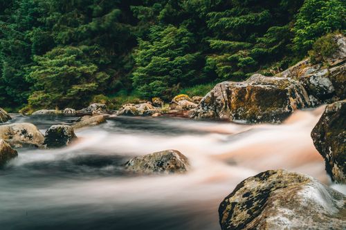 Free Peaceful river scene with smooth water flow and large rocks in Wicklow, Ireland. Stock Photo