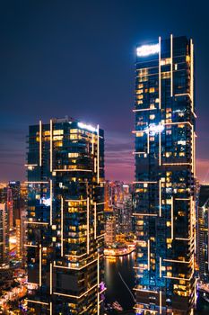 Stunning night view of Dubai's illuminated skyscrapers with vibrant city lights reflecting in the marina.