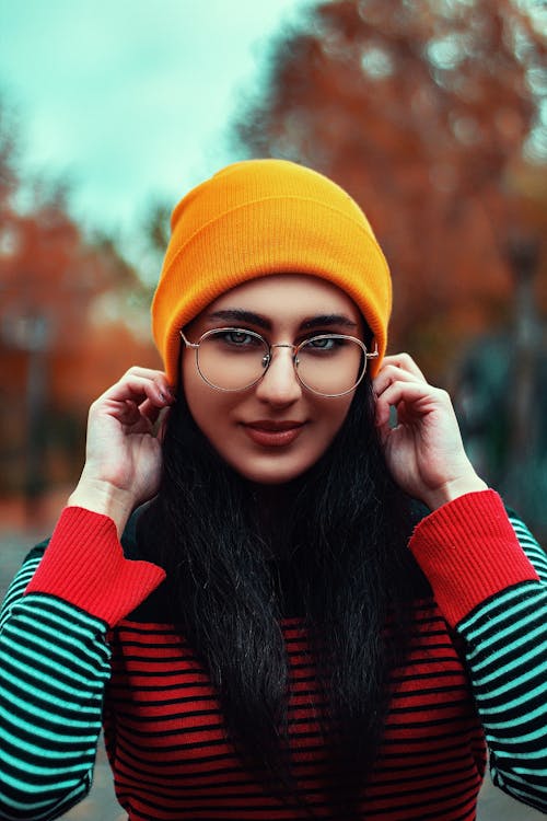 A Woman in Striped Long Sleeves Wearing a Yellow Knitted Cap and Eyeglasses