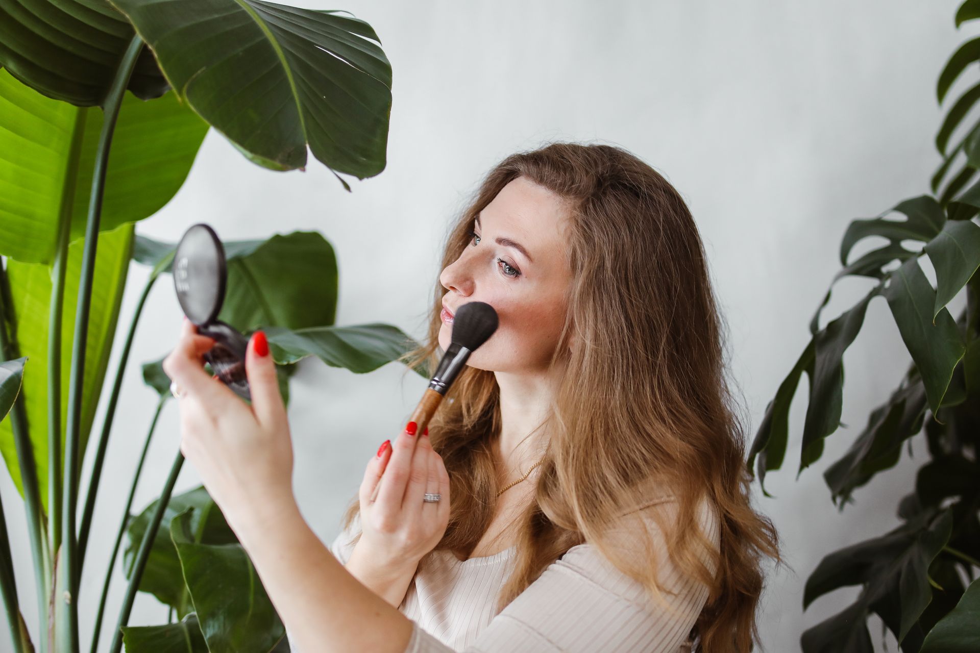 Photo of a Blonde Woman Applying Makeup on Her Cheeks