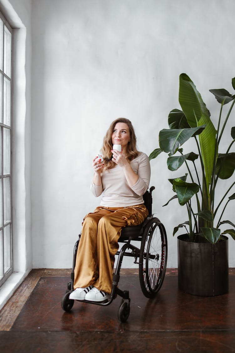 A Woman Sitting On A Wheelchair While Holding A Product