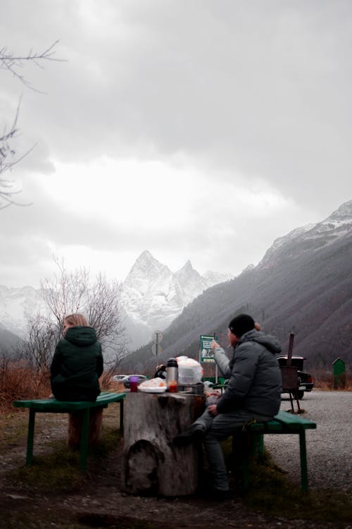 Unrecognizable travelers having lunch in mountainous terrain