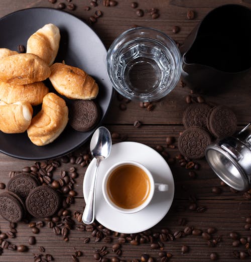 Free Top view arrangement of aromatic hot espresso in cup served on wooden table amidst coffee beans and chocolate cookies in modern cafe Stock Photo