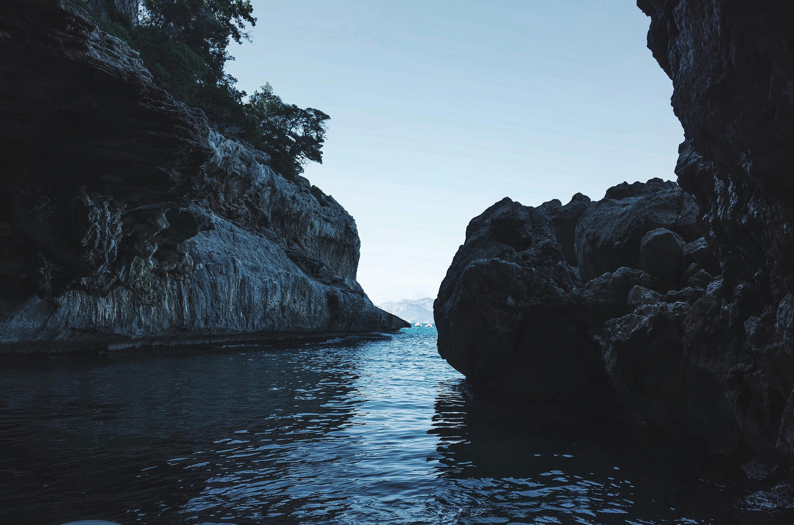 Stiniva Cove pebble beach enclosed by towering limestone cliffs under bright midday Adriatic sunlight