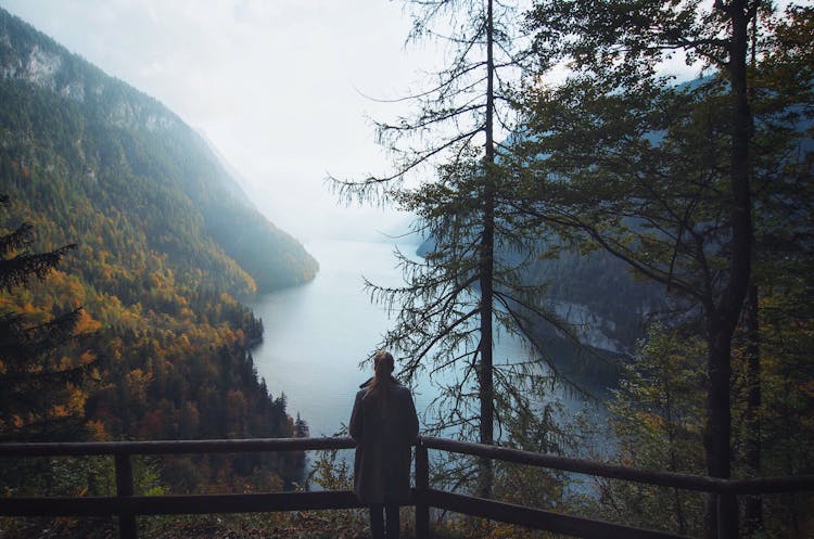 Woman Standing Overlooking The Waters Between Mountains