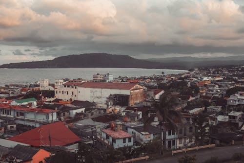 Scenic view of aged residential house facades against mount and sea under sky with fluffy clouds in city