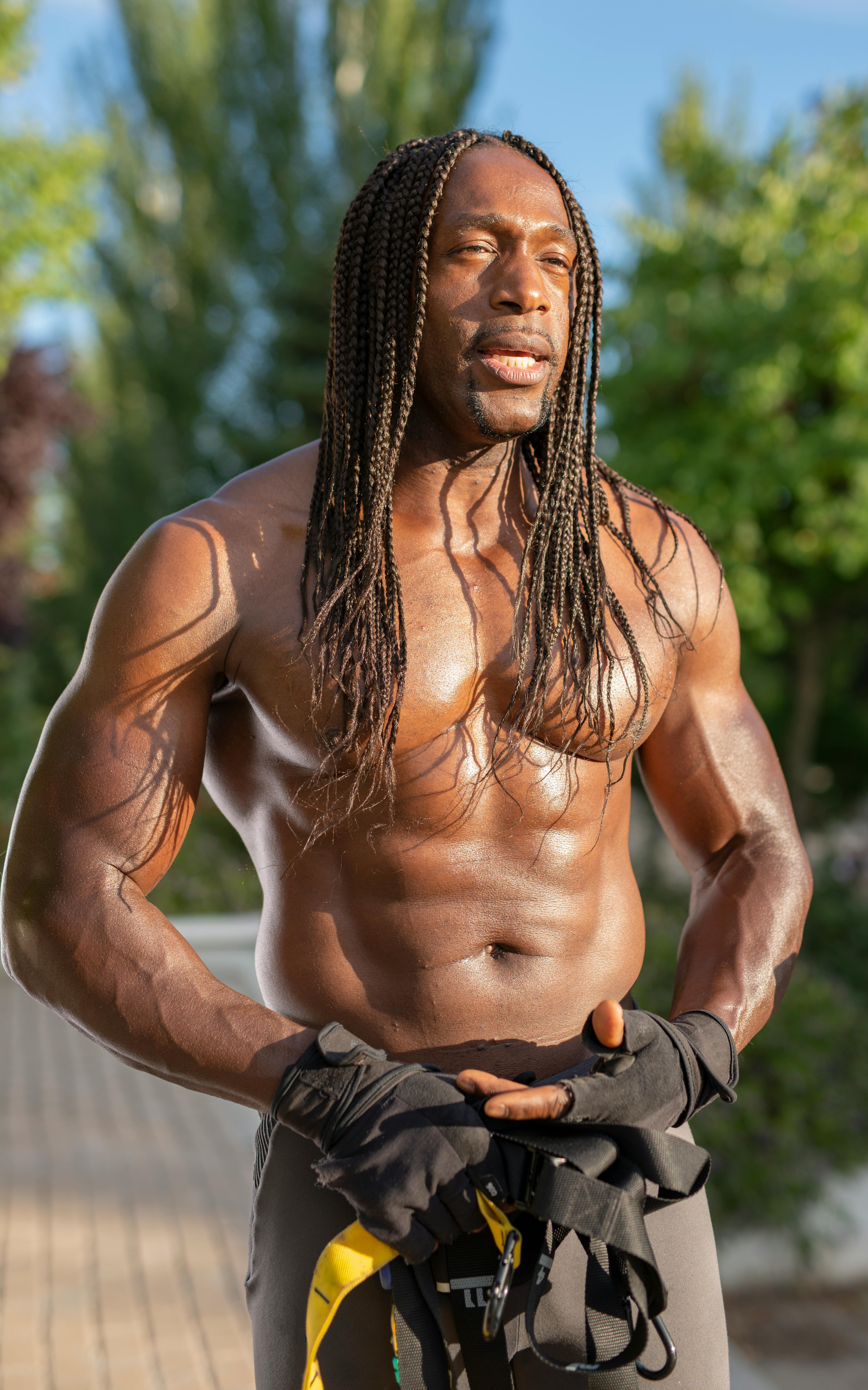 Shirtless, braided hair, muscular African American man outdoors in Madrid, showcasing fitness.