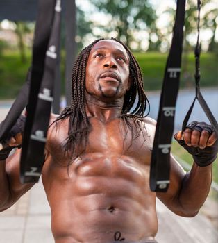 Athletic black man with braided hair exercising outdoors in Madrid on a sunny day.