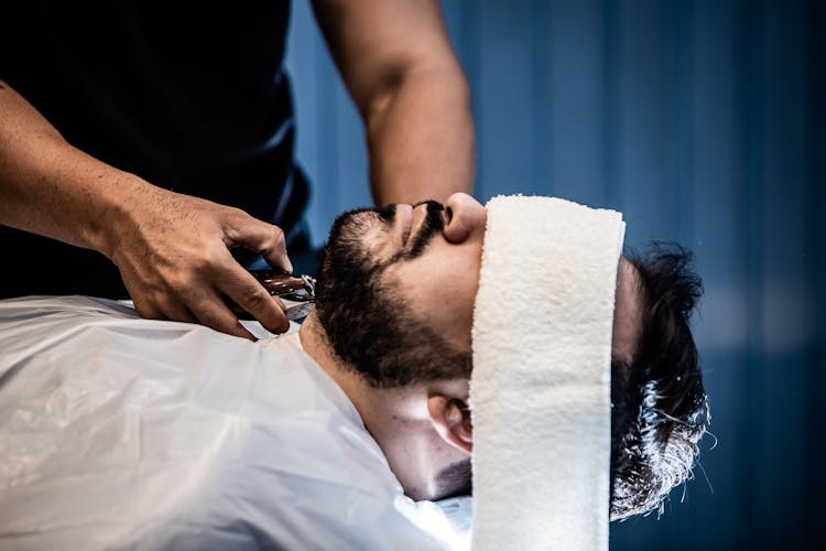 A Person Grooming A Man's  Beard