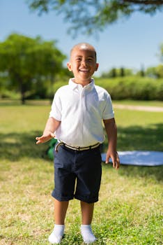 A happy young boy smiling broadly while standing in a sunny park, capturing the essence of joy and childhood.