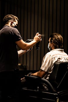 A barber wearing a mask styles a client's hair in a João Pessoa barbershop.