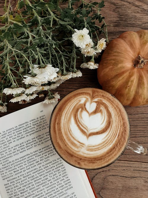 Free A Coffee Near the Open Book and Pumpkin on a Wooden Table Stock Photo