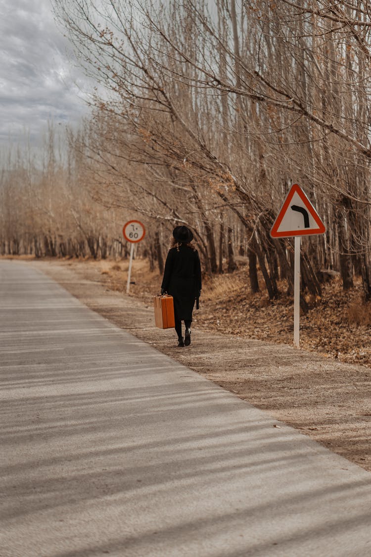 Woman With Old Heavy Suitcase Walking Near Asphalt Road