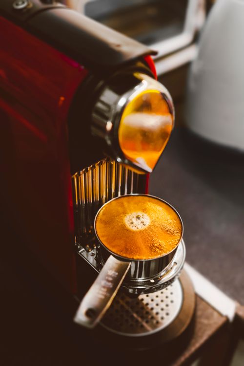 Free Close-up of espresso brewing in a red coffee machine indoors. Stock Photo